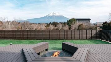 Une terrasse avec un foyer, une vue sur une montagne et une clôture en bois.
