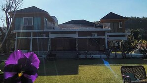 A two-story house with a covered patio area. - Tranquil Nature Resort (Dehradun)