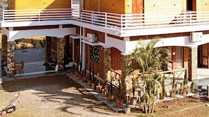A two-story house with a balcony, stone foundation, and a mountain backdrop. - Tranquil Nature Resort (Dehradun)