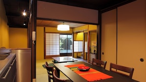 Una habitación japonesa tradicional con suelo de tatami, una mesa baja, sillas de madera y puertas correderas.