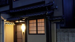 Una casa tradicional japonesa con techo de tejas, una puerta de madera y un camino de piedra que conduce a la entrada.