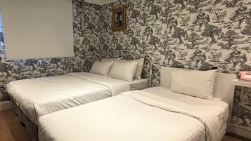 A room with two beds, a wooden nightstand, a wall-mounted picture, and a patterned wallpaper.