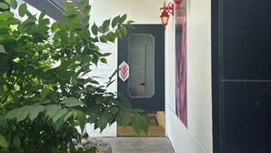Een moderne entree met een glazen deur, een rode lantaarn en een plant op de voorgrond.