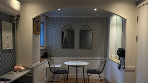 Een kleine kamer met een ronde tafel, twee stoelen, een telefoon en een spiegel.