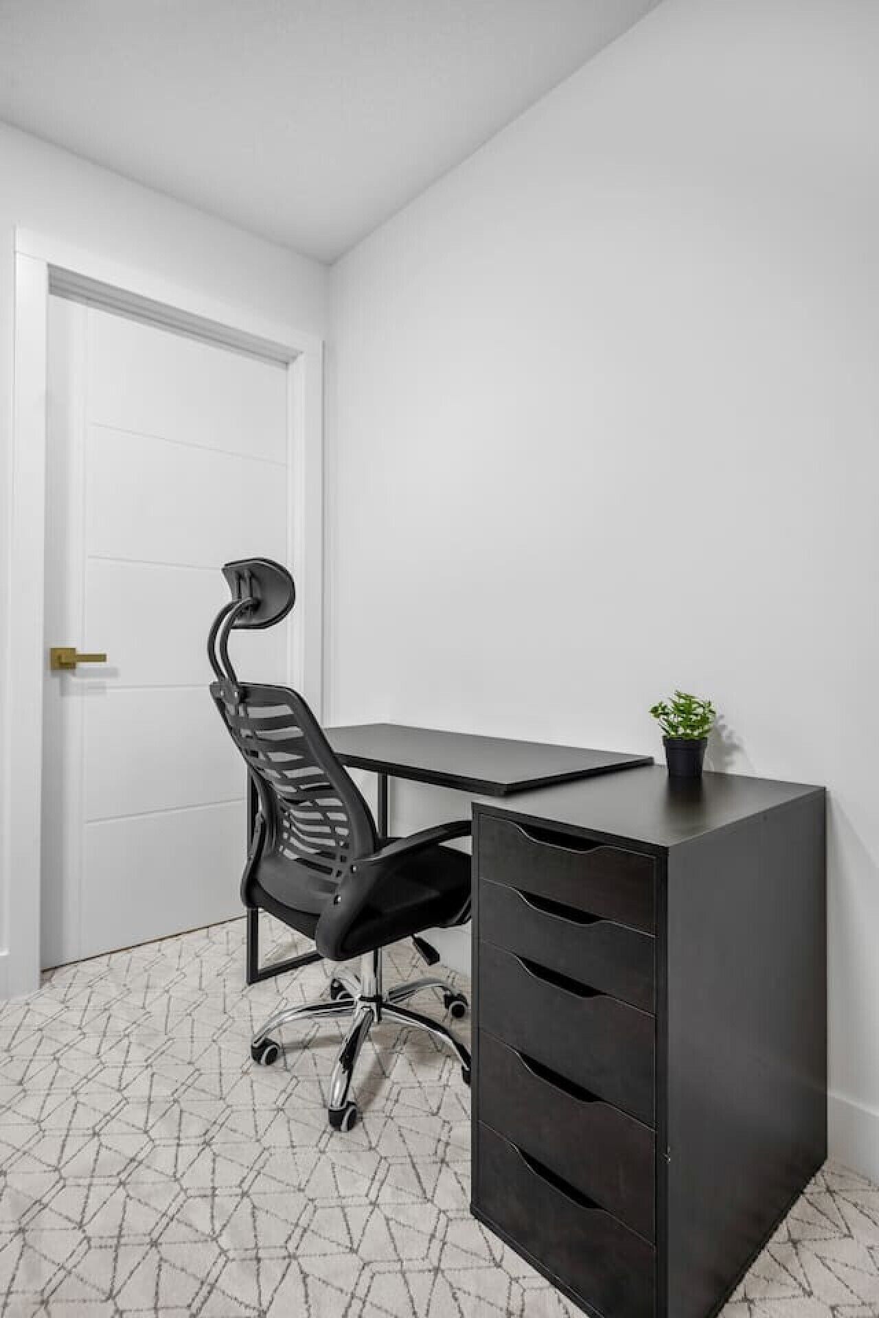 A modern office space with a desk, chair, and filing cabinet.