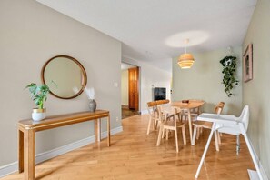 A modern interior with a wooden dining table, chairs, a console table with a mirror, and a hanging plant. - 3BR bungalow near Chinook Mall, office, sleeps 8 (Calgary)