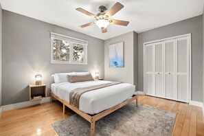 A bedroom with a bed, bedside lamps, a ceiling fan, a window, and a closet. - 3BR bungalow near Chinook Mall, office, sleeps 8 (Calgary)