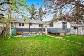 A two-story house with a covered patio, a fenced yard, and a satellite dish. - 3BR bungalow near Chinook Mall, office, sleeps 8 (Calgary)