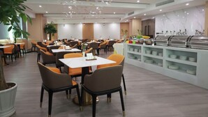 A modern dining area with tables and chairs, a buffet station, and decorative hanging elements.