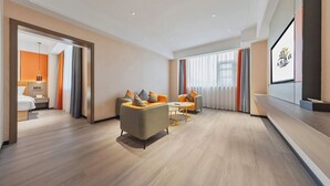 A modern hotel room with a sofa set, a dining table, and a large window with curtains.