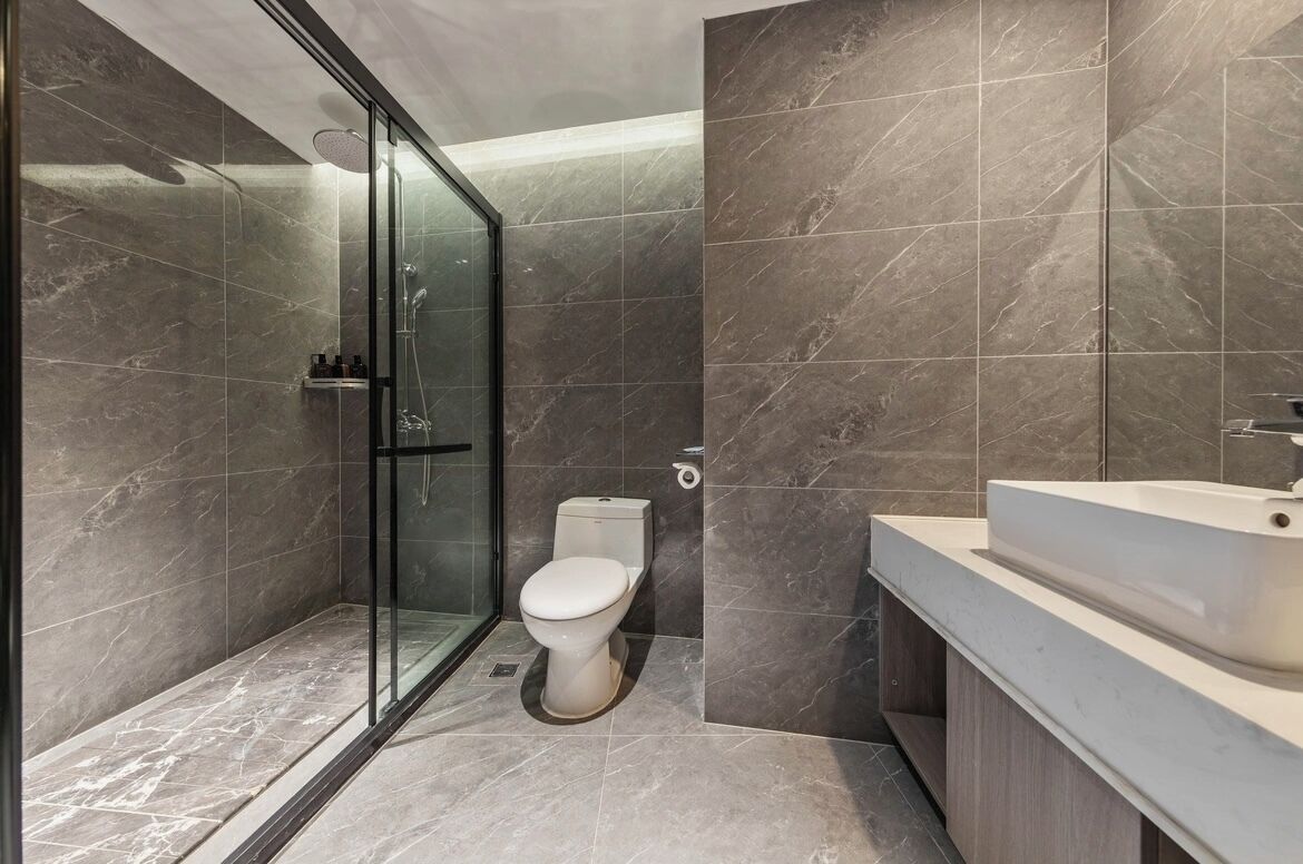 Un baño moderno con cabina de ducha de vidrio, inodoro y lavamanos.