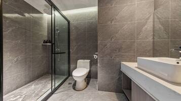 Un baño moderno con cabina de ducha de vidrio, inodoro y lavamanos.