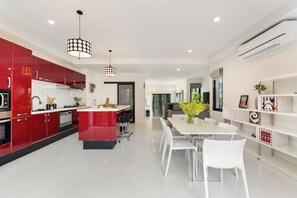 A modern kitchen with red cabinets, a central island, and pendant lighting.
