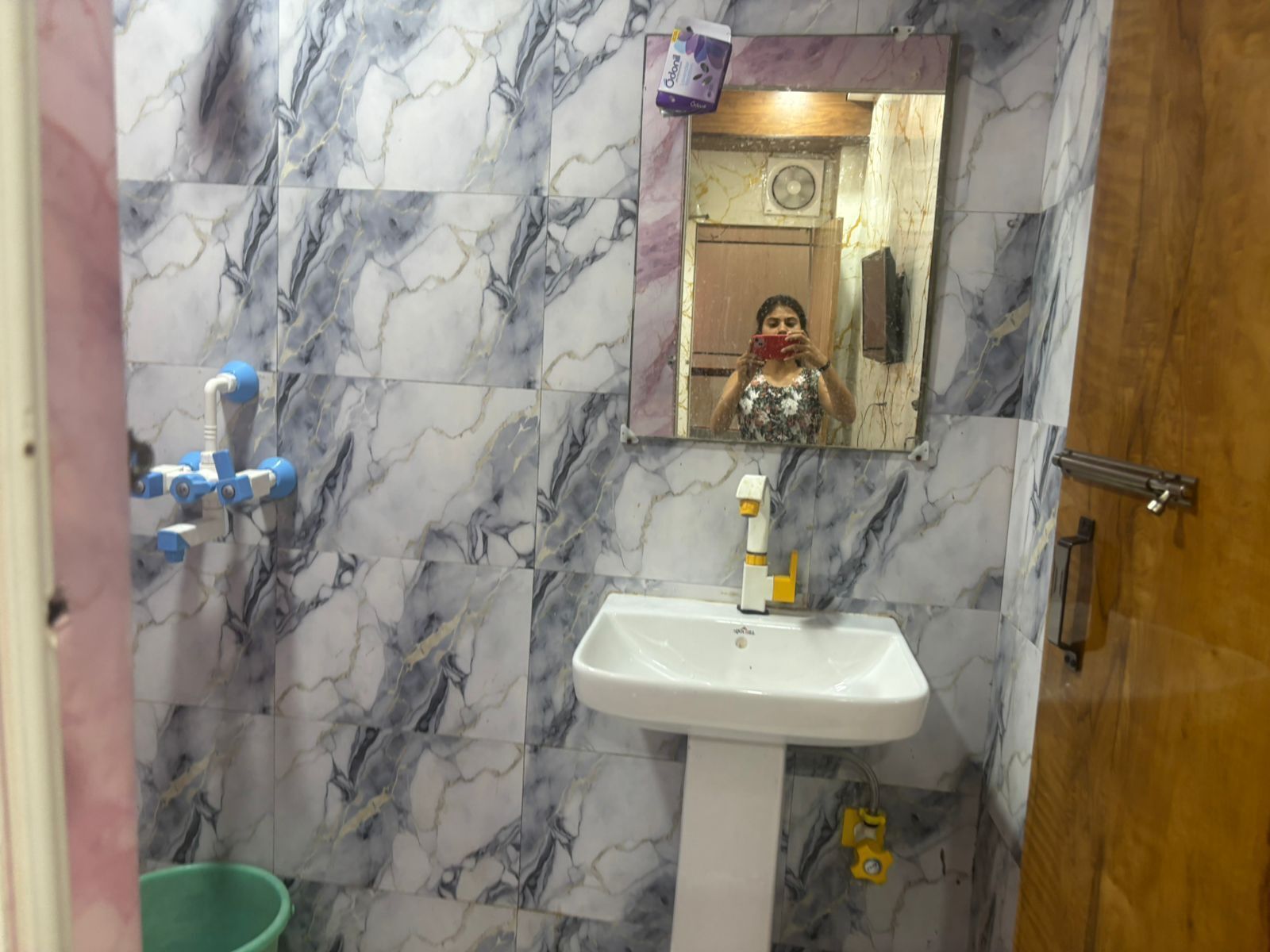 A bathroom with marble walls, a white sink, and a mirror.