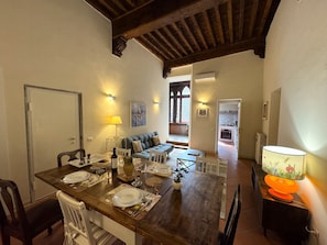 A dining area with a wooden table set for four, a sofa, and a lamp. - Apartment in Lucca with 4 bedrooms sleeps 8 (Lucca)