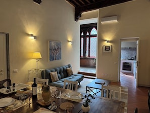 A dining area with a table set for four, a sofa, and a kitchen in the background. - Apartment in Lucca with 4 bedrooms sleeps 8 (Lucca)