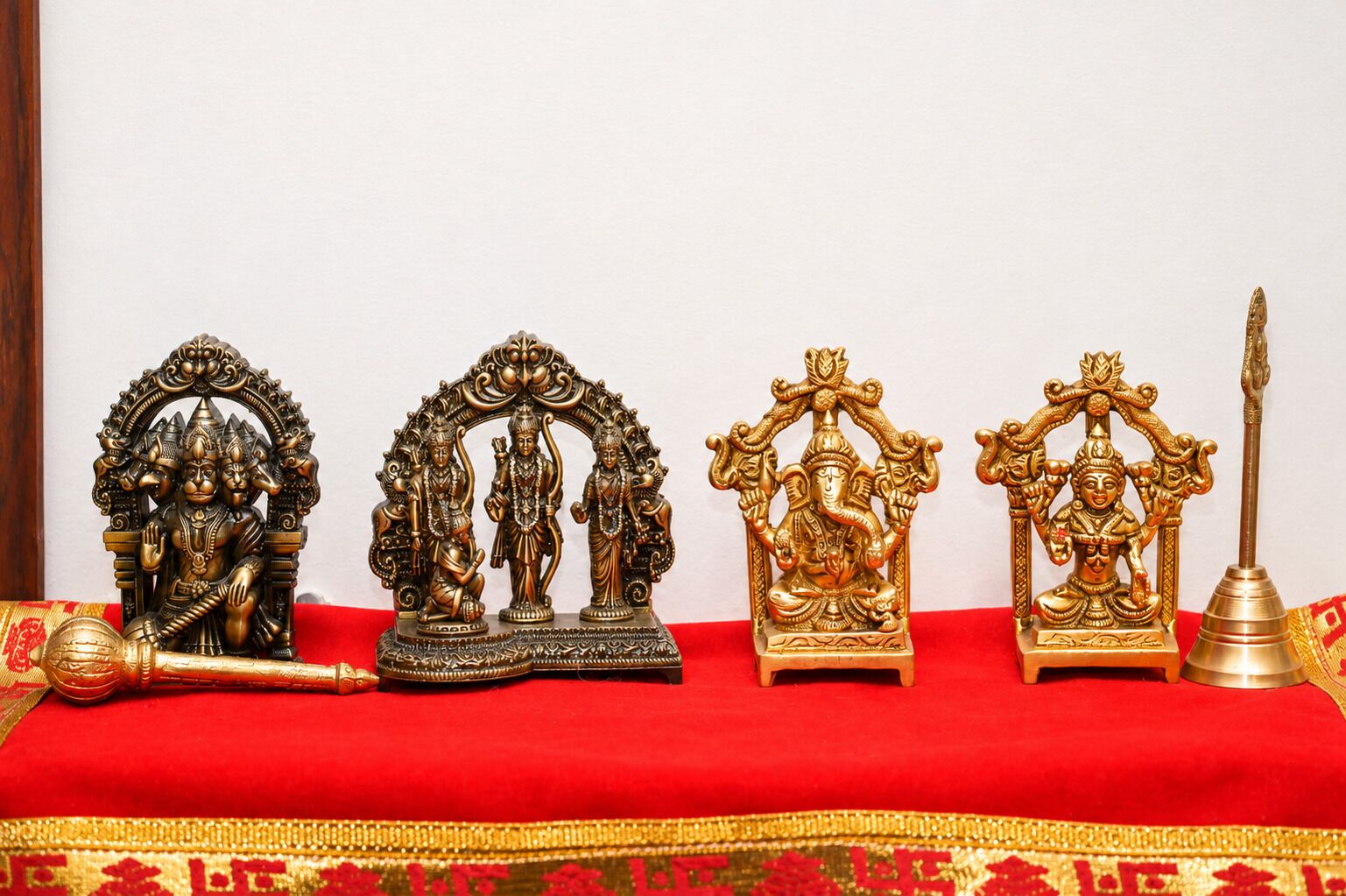 A row of religious statues on a red cloth.