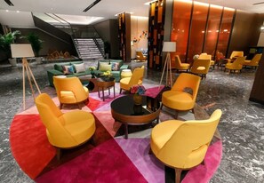 Eine moderne Lobby mit Treppe, Sitzgelegenheit mit gelben Stühlen, einem grünen Sofa und einem Couchtisch.