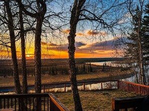 A view of a lake with trees and a wooden deck.