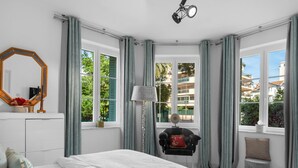 A bedroom with a bed, a desk, a chair, a lamp, a mirror, and large windows with curtains. - Luxurious 3 bedroom apartment, in the heart Cannes (Cannes)