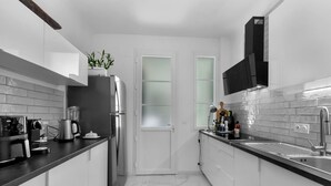 A modern kitchen with white cabinets, a stainless steel refrigerator, a coffee maker, and a plant on the counter. - Luxurious 3 bedroom apartment, in the heart Cannes (Cannes)