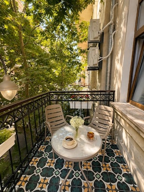 A balcony with a round table, two chairs, a vase with flowers, and a cup of tea. - Amara Boutique Hotel (Baku)