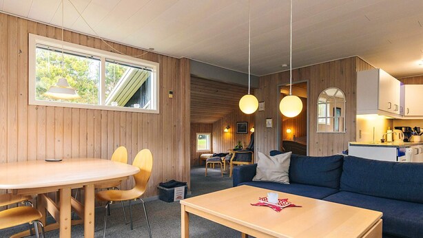 Une pièce chaleureuse avec une table à manger en bois, des chaises, un canapé et un coin cuisine.