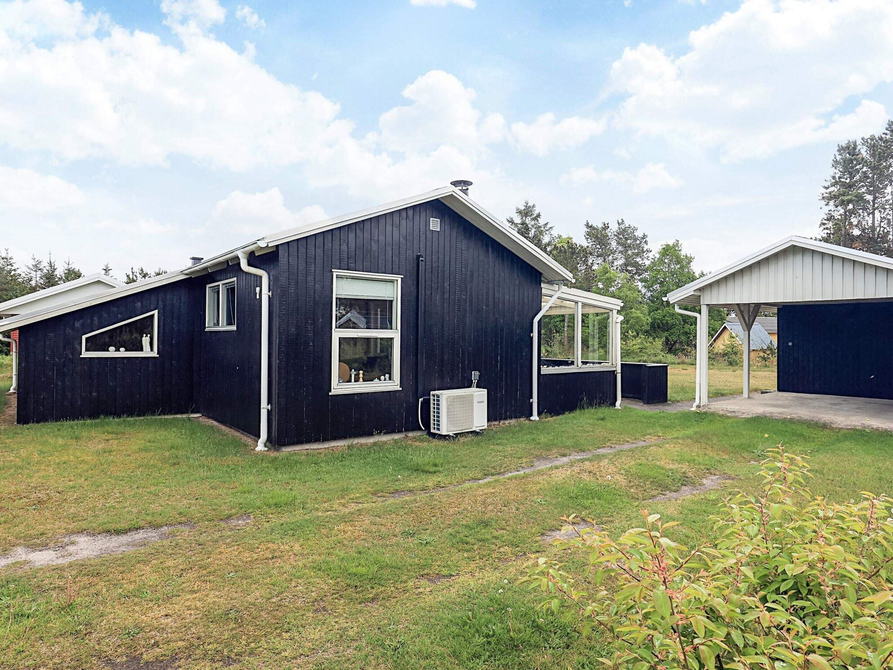 A black building with a covered porch and a garage.