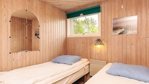 Une chambre avec deux lits, une fenêtre donnant sur un beau paysage, une lampe fixée au mur et un miroir.