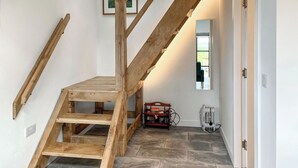 Un escalier en bois offrant une vue sur une pièce dotée d’une fenêtre et d’une porte.