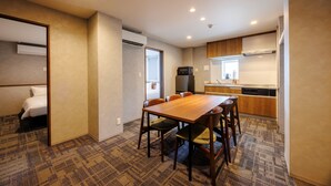 Habitación de hotel con mesa, sillas, cama y kitchenette.