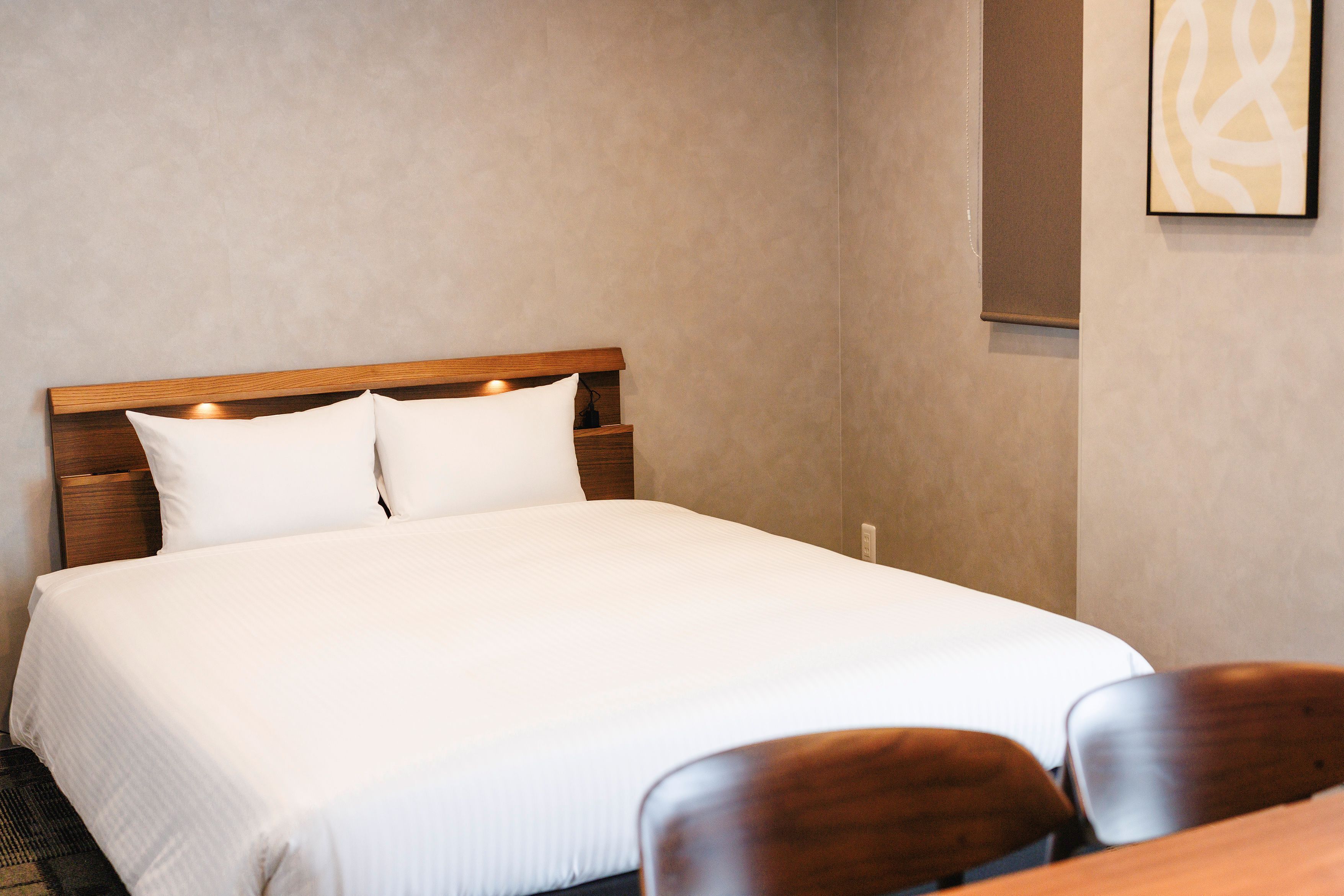 Une chambre d’hôtel avec un lit, une tête de lit en bois et une œuvre d’art accrochée au mur.