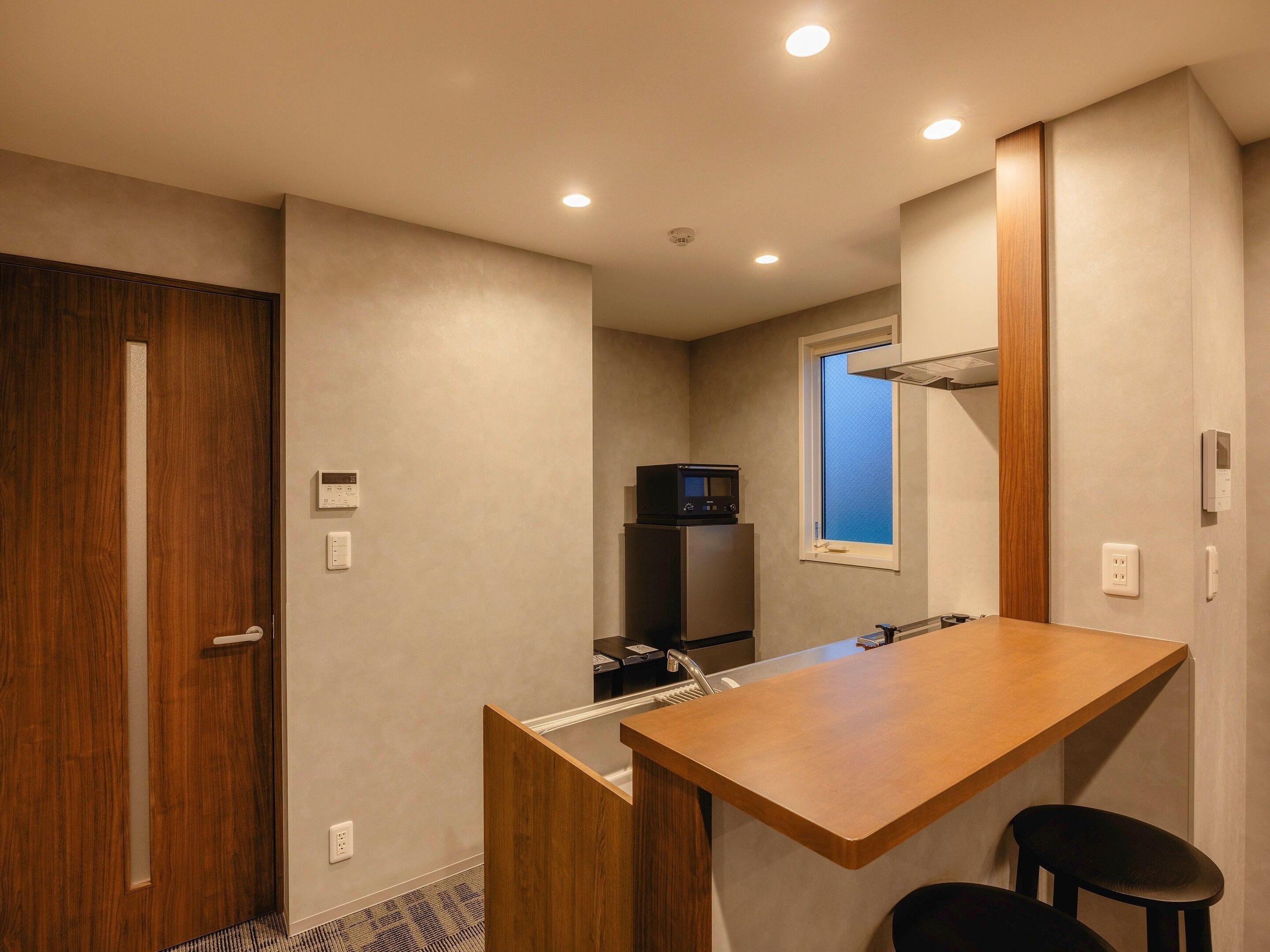 Cocina compacta con encimera de madera, microondas y ventana.