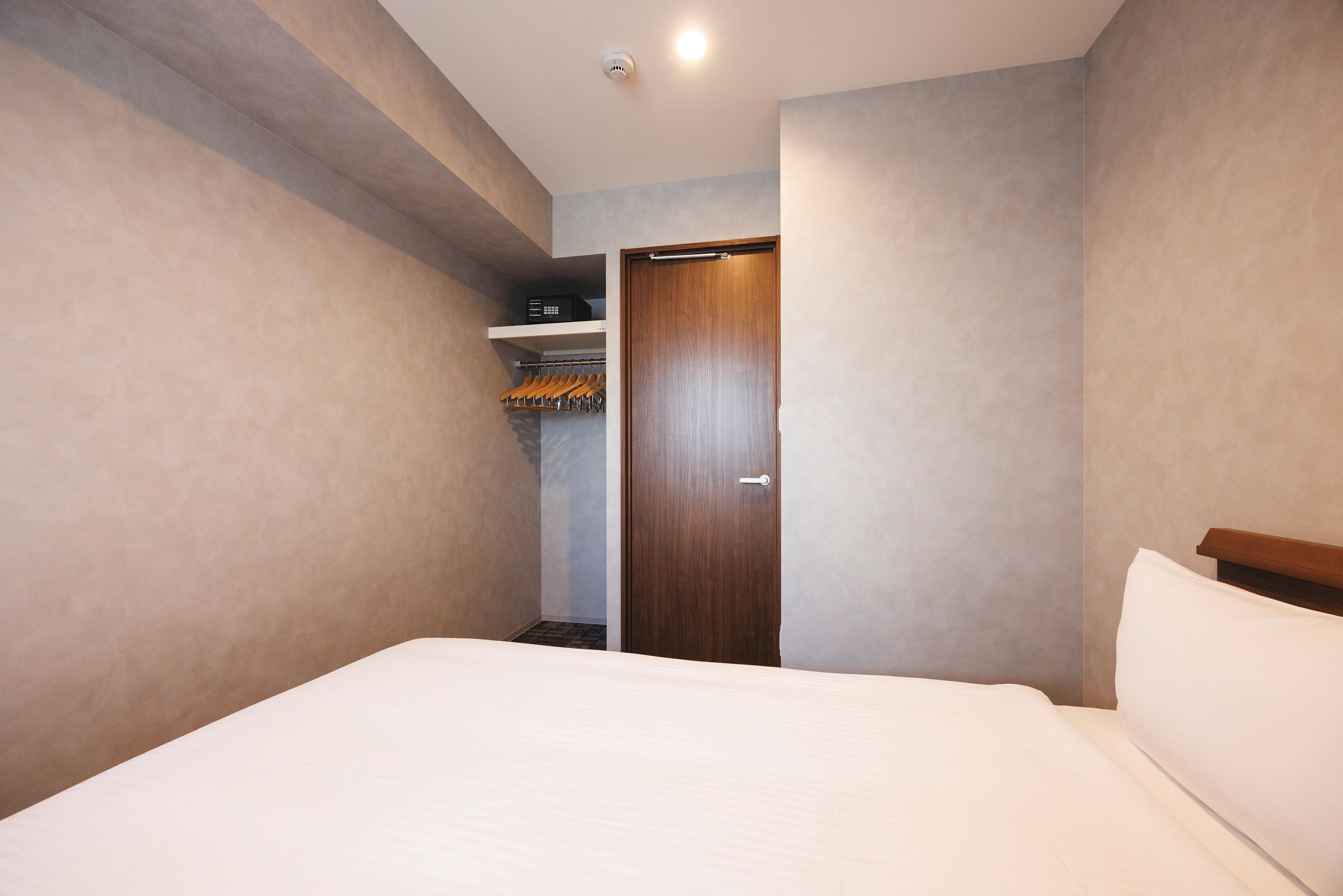 Une chambre d’hôtel avec un lit, une armoire et un porte-manteau.