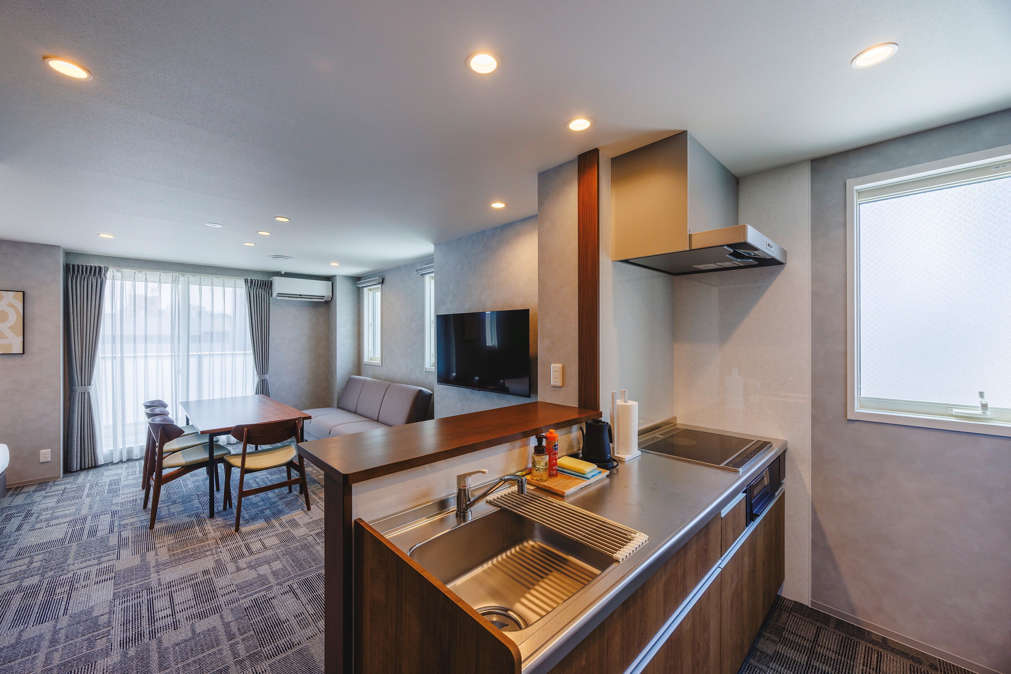 Una habitación de hotel moderna con kitchenette, comedor y sala de estar.