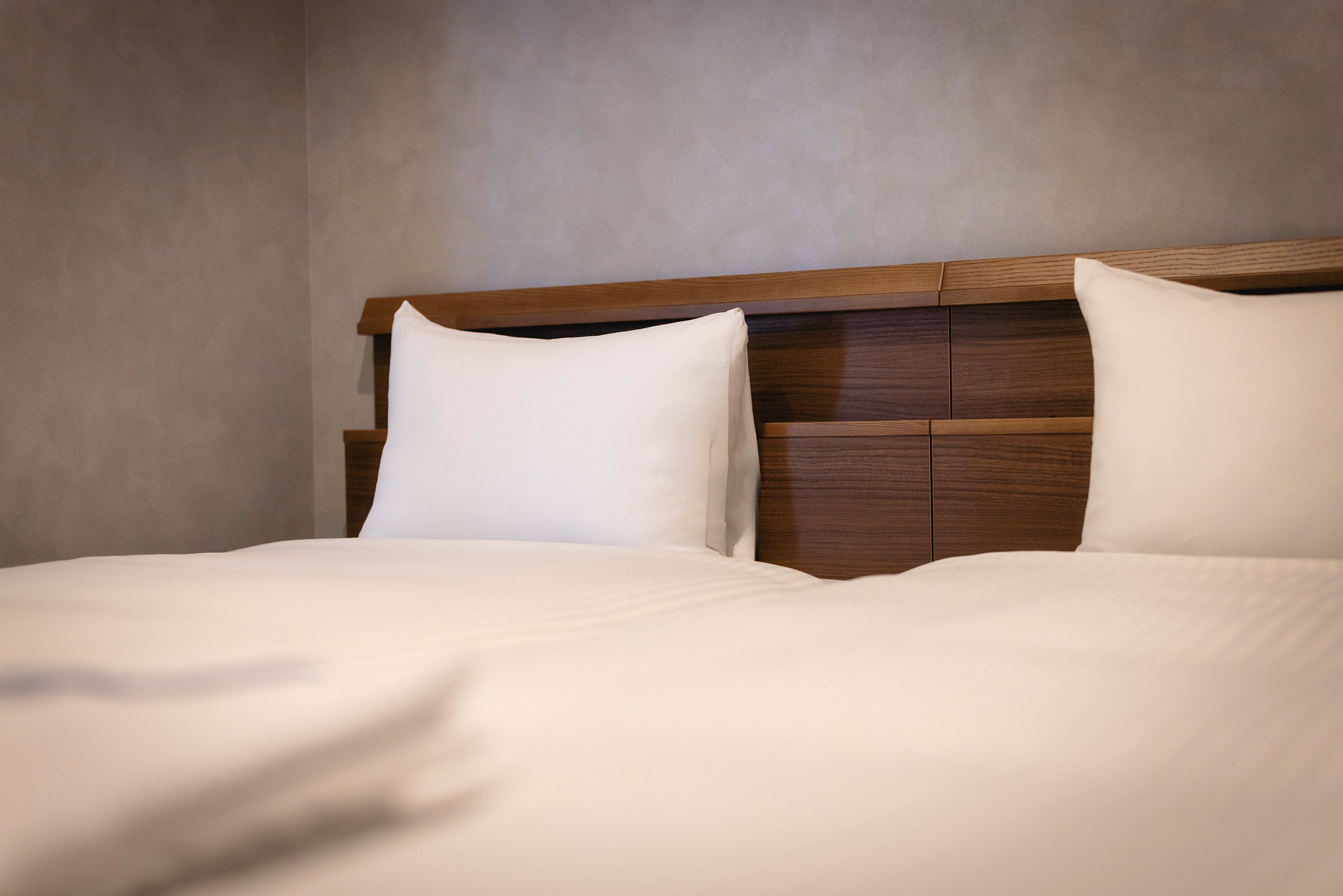 A neatly made bed with a wooden headboard and white bedding.