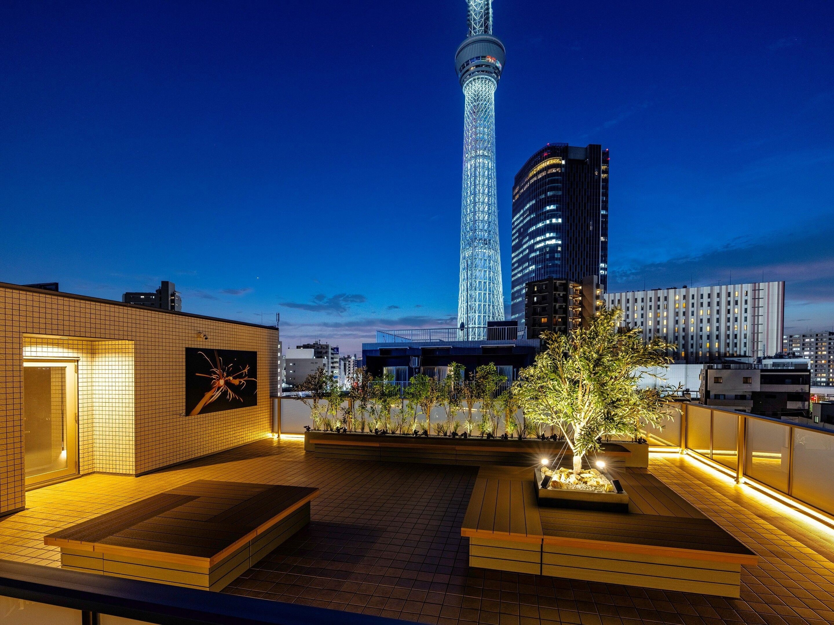 Una terraza en la azotea con vistas a una torre alta y edificios circundantes.