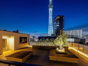 A rooftop terrace with a view of a tall tower and surrounding buildings. - KOKO HOTEL Residence Tokyo Oshiage (Sumida-ku)