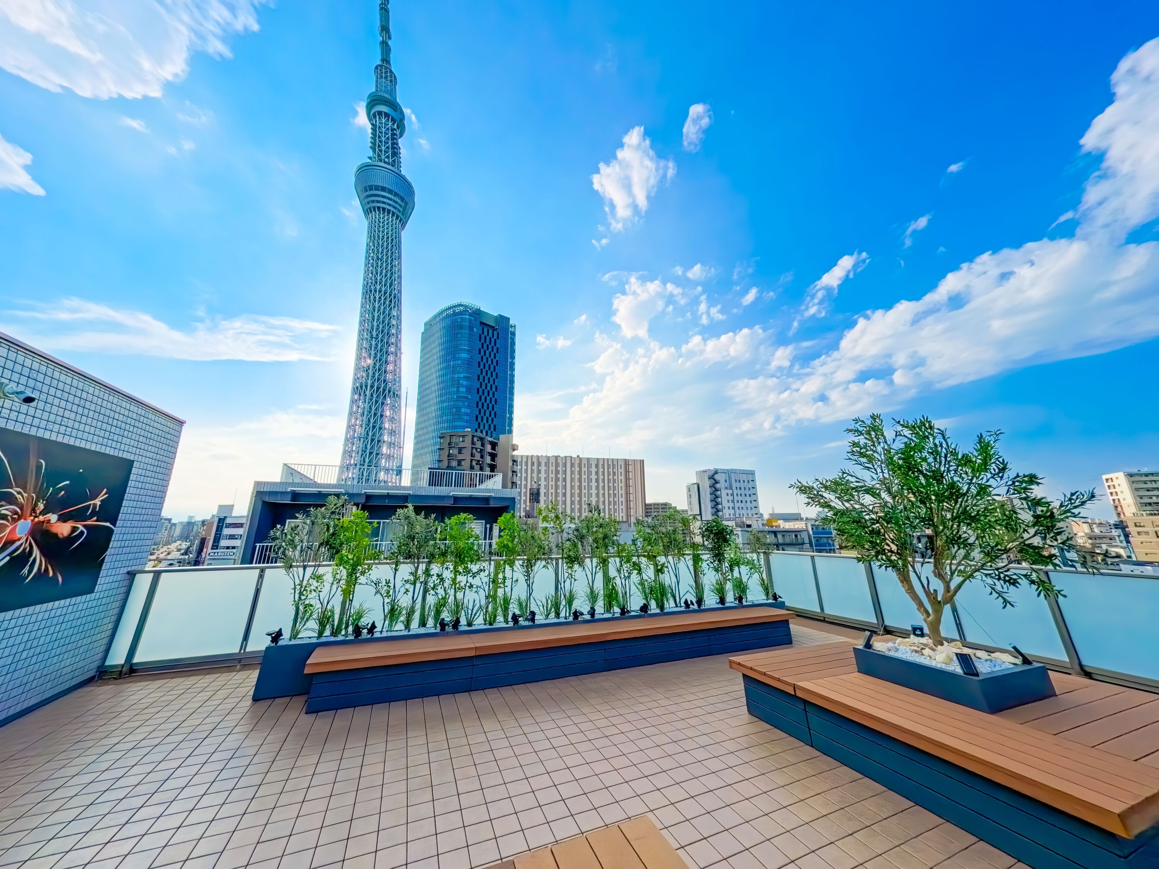 A rooftop terrace with a view of the tower, seating areas, and potted plants.