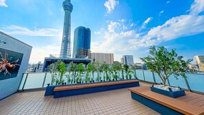 Terraza en la azotea con vistas a la torre, zonas de estar y plantas en macetas.
