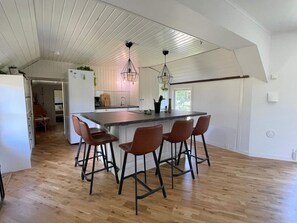 A modern kitchen with a central island, bar stools, and pendant lighting. - 4 Star Holiday Home in Farjestaden (Farjestaden)