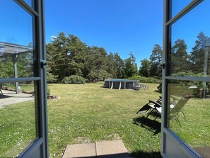 An open door leading to a backyard with a pool, a covered patio, and a lawn. - 4 Star Holiday Home in Farjestaden (Farjestaden)