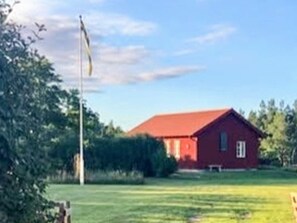 A red building with a flagpole in front, surrounded by greenery. - 4 Star Holiday Home in Farjestaden (Farjestaden)