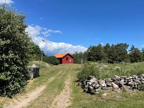 A rural landscape with a red house, a dirt path leading to it, and a stone wall. - 4 Star Holiday Home in Farjestaden (Farjestaden)