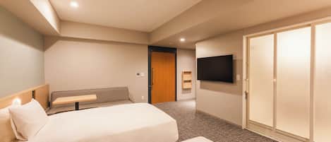 Ein Hotelzimmer mit zwei Betten, einem Fernseher, einer Schiebetür und einer Bank.