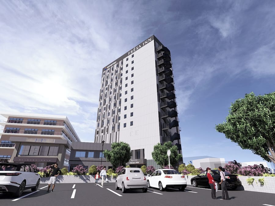 Moderni, useita kerroksia sisältävä hotellirakennus, jossa on suuri, näkyvä kyltti, jossa lukee »FRESA INN», sekä useita autoja sisältävä pysäköintialue.