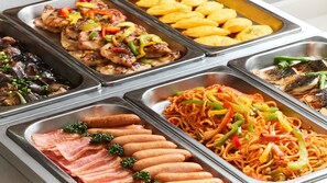 A buffet with various dishes including noodles, meats, and vegetables.