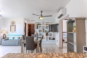 A modern living room with a dining area, a ceiling fan, a mounted TV, and a decorative wall piece. - Bright & Comfortable Condo in Heart of Versalles! 2BD Condo for rent in Versalle (Puerto Vallarta)