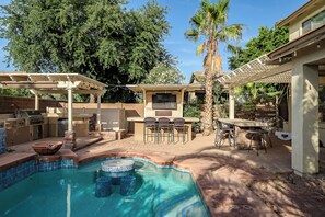 Um quintal com piscina, cozinha externa e área de estar.