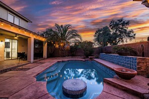 A swimming pool with a mosaic deck, surrounded by a patio area with string lights, palm trees, and a sunset view. - Spacious 5BR Gilbert Home w Pool for Getaway for Family (Gilbert)